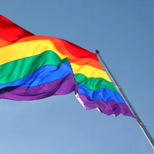 Rainbow Flag flying against blue sky - Symbol of Gay Pride