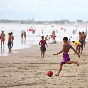 Tourists on holiday playing football on Legian Beach, Denpasar, Bali, Indonesia