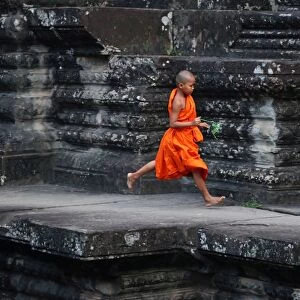 Young Buddhist monk running at Angkor Wat Temple, Cambodia