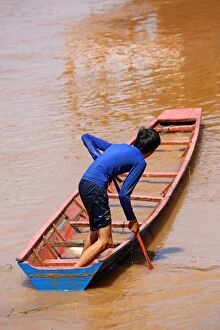 Images Dated 13th September 2015: Boy paddling a flooded sinking boat on the Mekong River in Luang Prabang, Laos