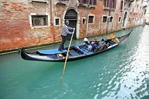 Venice Collection: Gondoleer poling a gondola carrying tourists along a canal, in Venice, Italy