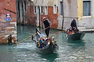Images Dated 9th February 2013: Gondoleers poling gondolas carrying tourists along a canal, in Venice, Italy