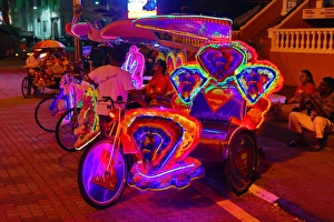 Illuminated decorated kitsch cycle trishaw rickshaw with soft toys at night in Malacca, Malaysia Illuminated decorated kitsch cycle trishaw rickshaw with soft toys at night in Malacca, Malaysia