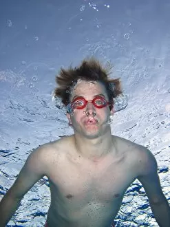Images Dated 9th April 2011: Man swimming underwater wearing goggles blowing bubbles