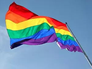 Trending: Rainbow Flag flying against blue sky - Symbol of Gay Pride