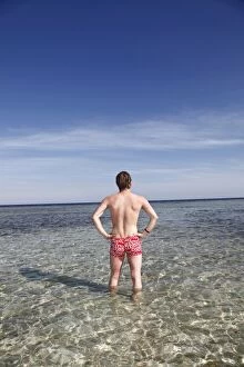 Images Dated 9th April 2011: Rear view of a man on summer holiday standing in the sea on the beach
