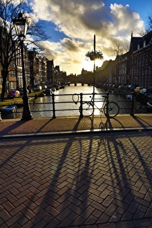 Silhouette of a parked bicycle and its shadow on a bridge over a canal in Amsterdam, Holland Silhouette of a parked bicycle and its shadow on a bridge over a canal in Amsterdam, Holland