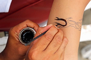 Tattoos for tourists. Temporary henna tattoo being applied, Legian Beach, Denpasar, Bali, Indonesia Tattoos for tourists. Temporary henna tattoo being applied, Legian Beach, Denpasar, Bali, Indonesia