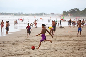 Tourists on holiday playing football on Legian Beach, Denpasar, Bali, Indonesia Tourists on holiday playing football on Legian Beach, Denpasar, Bali, Indonesia