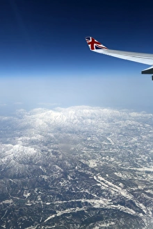 View out of an aircraft window with mountains and a plane wing View out of an aircraft window with mountains and a plane wing